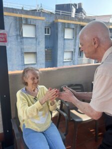 Persona mayor utilizando un dispositivo de teleasistencia en casa junto a un familiar, servicio de apoyo y seguridad para mayores – La Vostra Llar